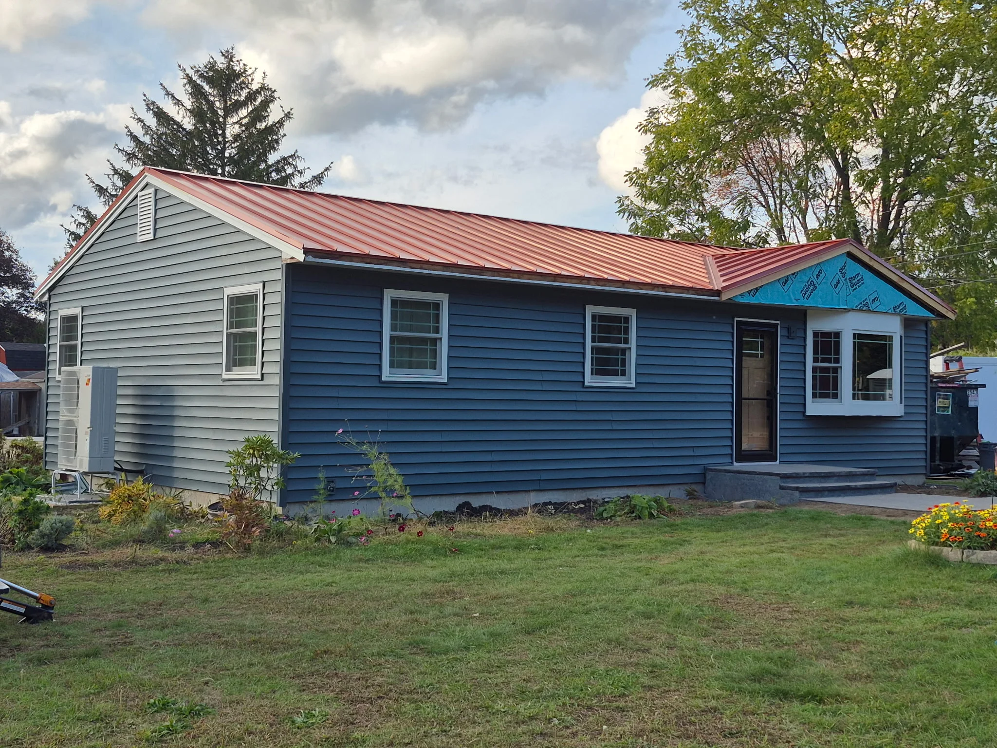 Metal standing seam roof and vinyl siding on residential home with multiple windows