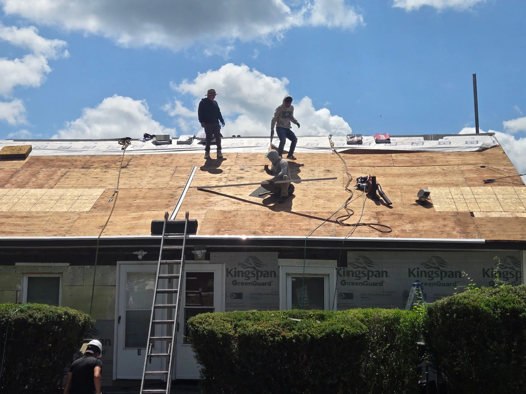 Roofers installing Kingspan GreenGuard materials on commercial building roof with plywood decking